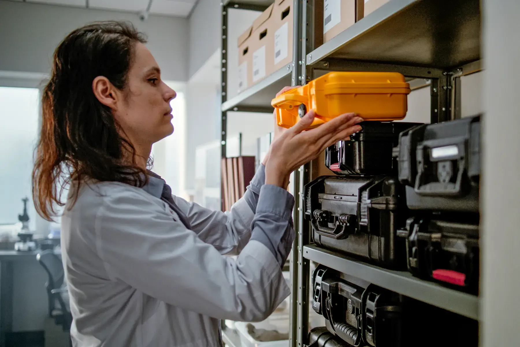 Modern archaeological science laboratory: female paleontologist in lab coat takes protective case with scientific research fossil materials.